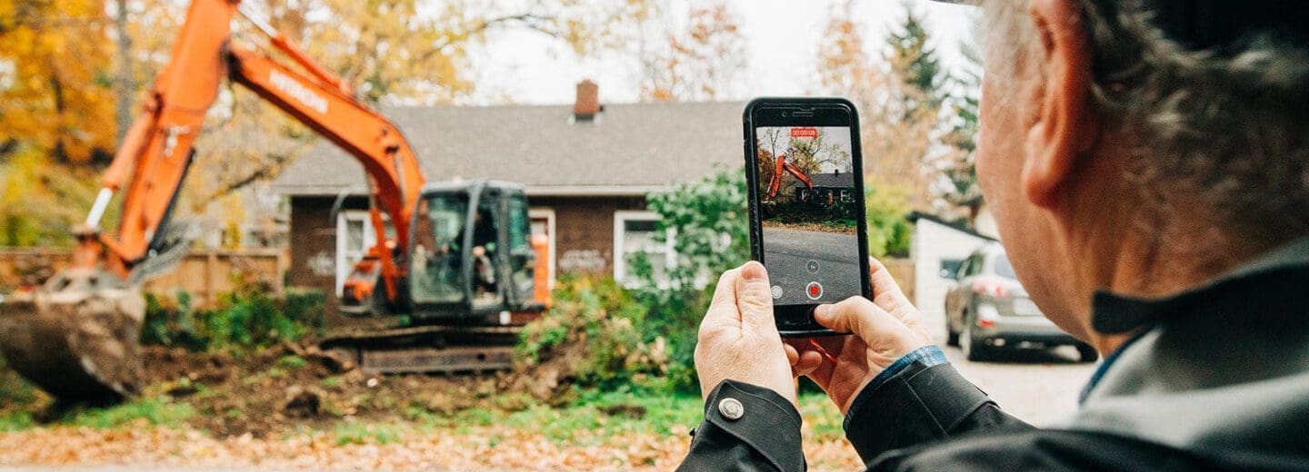 man taking photo of home on smartphone