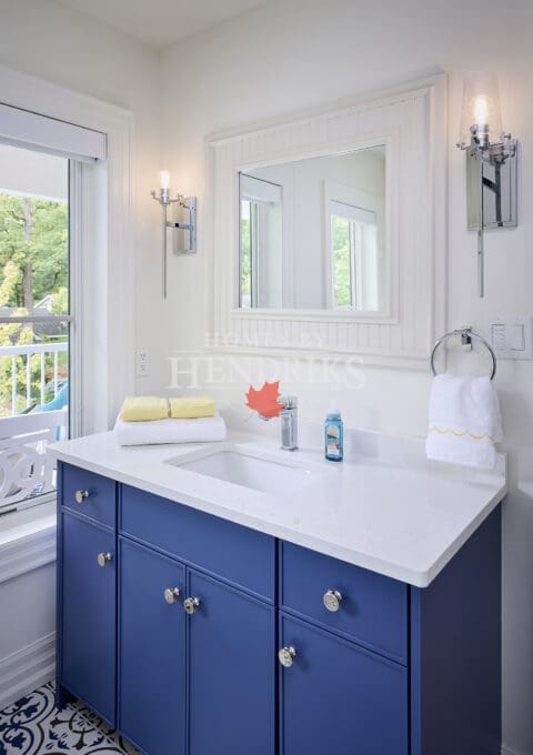 Interior view of a guest bedroom bathroom featuring a blue vanity, complementing the space with a fresh and stylish design, along with modern fixtures and elegant accents.