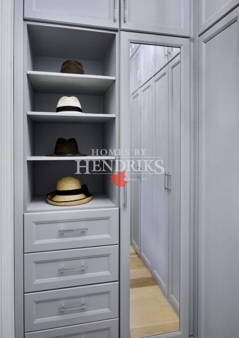 Interior view of a spacious walk-in closet with grey cabinetry, showcasing organized shelving, hanging space, and a stylish layout for easy access to clothing and accessories.