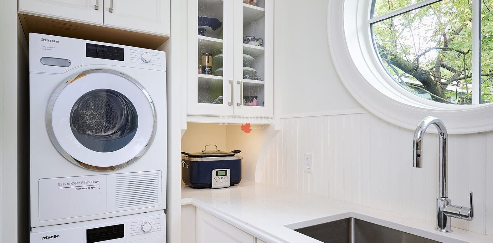 Interior view of a laundry room with modern appliances, white cabinetry, and a functional layout, providing a bright and organized space for chores.