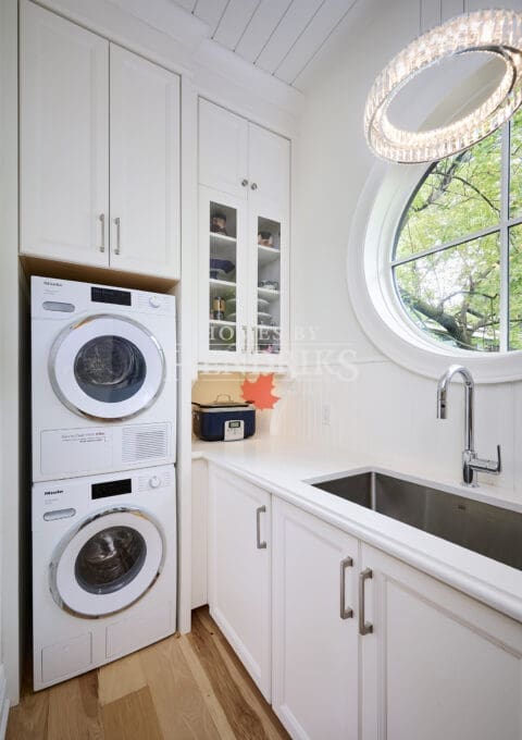 Interior view of a laundry room with modern appliances, white cabinetry, and a functional layout, providing a bright and organized space for chores.