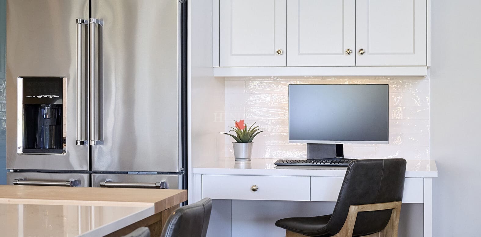 A functional kitchen work nook featuring custom cabinetry and a spacious countertop, perfect for office tasks.