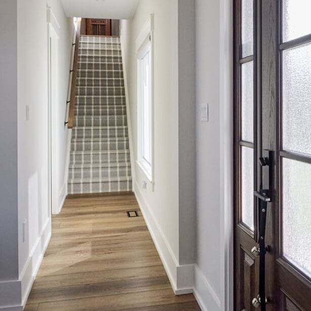 The entryway is highlighted by a custom wooden door with intricate detailing, framed by natural stone accents.