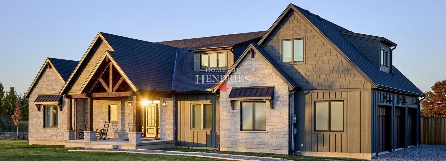 The front elevation of the home showcases a harmonious blend of Hardie board and batten siding with Hardie shake accents, creating a timeless yet contemporary look. Custom Douglas fir timber framing adds warmth and character, while natural stone masonry enhances the rustic charm.
