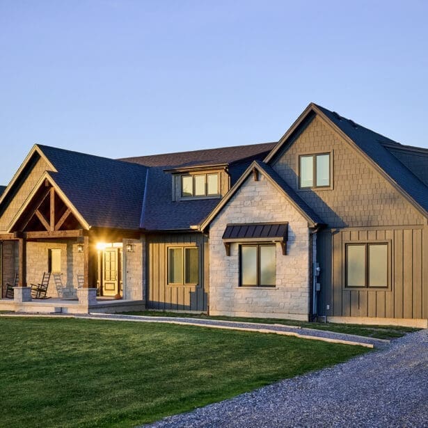 The front elevation of the home showcases a harmonious blend of Hardie board and batten siding with Hardie shake accents, creating a timeless yet contemporary look. Custom Douglas fir timber framing adds warmth and character, while natural stone masonry enhances the rustic charm.