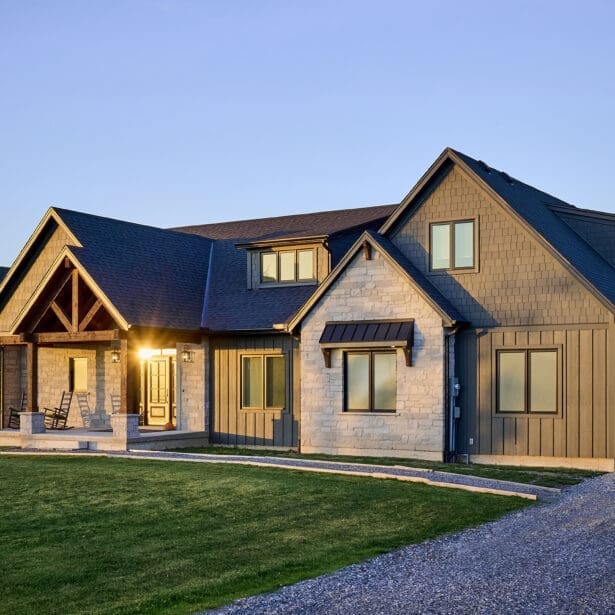 The front elevation of the home showcases a harmonious blend of Hardie board and batten siding with Hardie shake accents, creating a timeless yet contemporary look. Custom Douglas fir timber framing adds warmth and character, while natural stone masonry enhances the rustic charm.