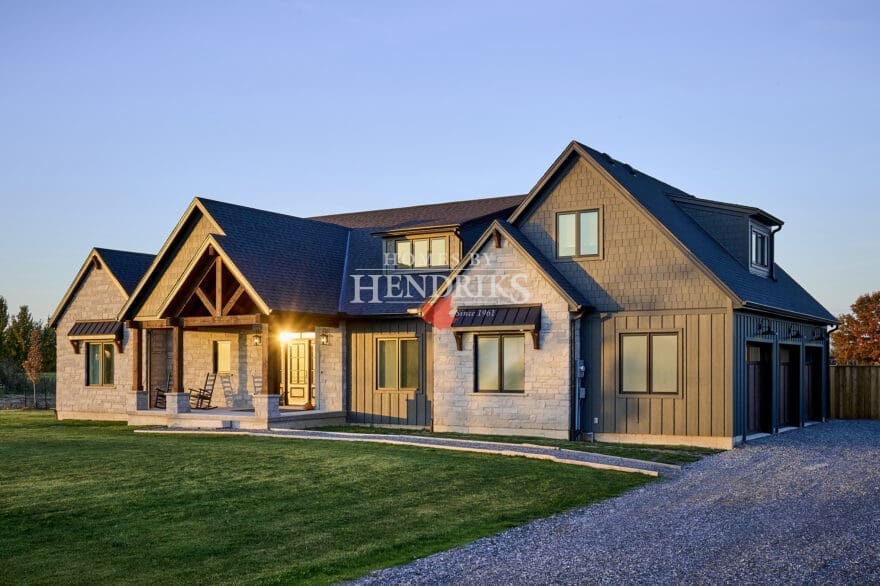 The front elevation of the home showcases a harmonious blend of Hardie board and batten siding with Hardie shake accents, creating a timeless yet contemporary look. Custom Douglas fir timber framing adds warmth and character, while natural stone masonry enhances the rustic charm.