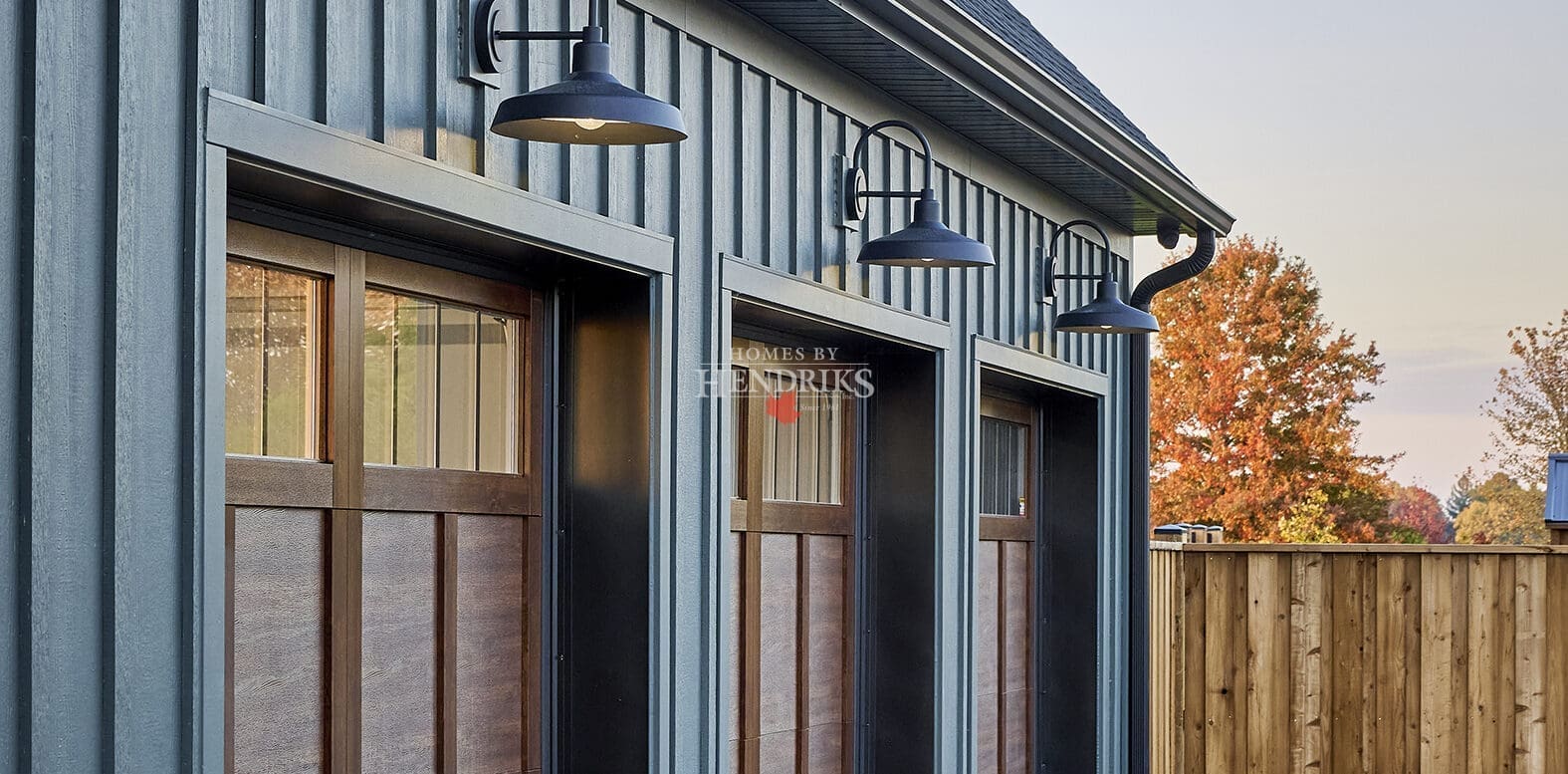 Custom wood garage doors with rich, natural wood tones and intricate detailing, adding warmth and charm to the home’s exterior.