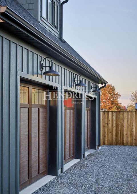 Custom wood garage doors with rich, natural wood tones and intricate detailing, adding warmth and charm to the home’s exterior.