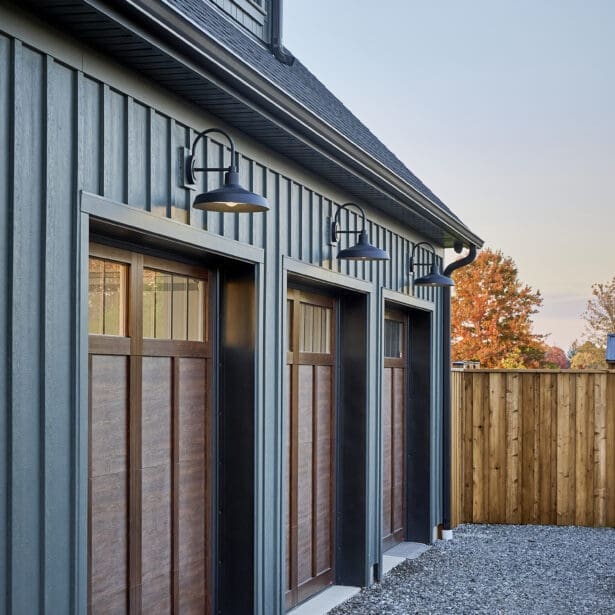 Custom wood garage doors with rich, natural wood tones and intricate detailing, adding warmth and charm to the home’s exterior.