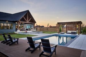 A sparkling, well-designed pool surrounded by a spacious patio and lush landscaping, offering a serene outdoor retreat.