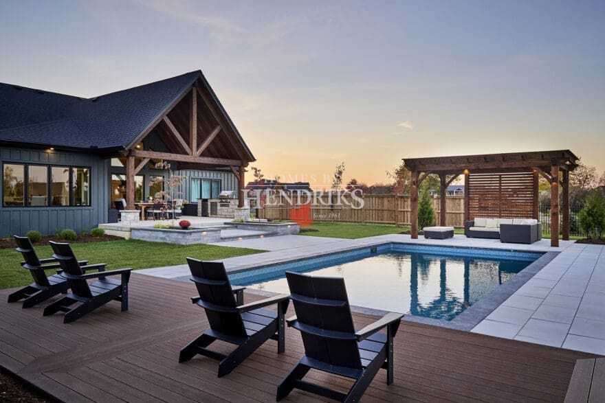 A sparkling, well-designed pool surrounded by a spacious patio and lush landscaping, offering a serene outdoor retreat.
