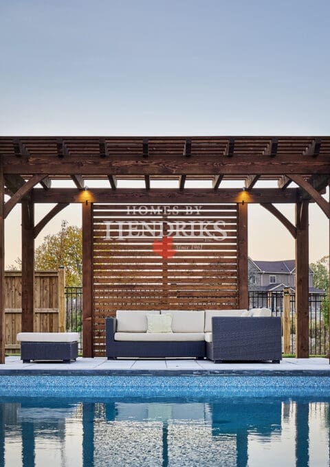 A stylish poolside pergola with rustic timber framing, providing shade and an elegant focal point near the pool.