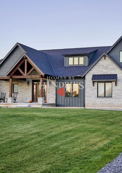 The front exterior of the home features a beautiful blend of Hardie board and batten siding, complemented by Hardie shake accents that create a timeless yet contemporary look. Custom Douglas fir timber framing adds warmth and character, while natural stone masonry enhances the rustic charm.