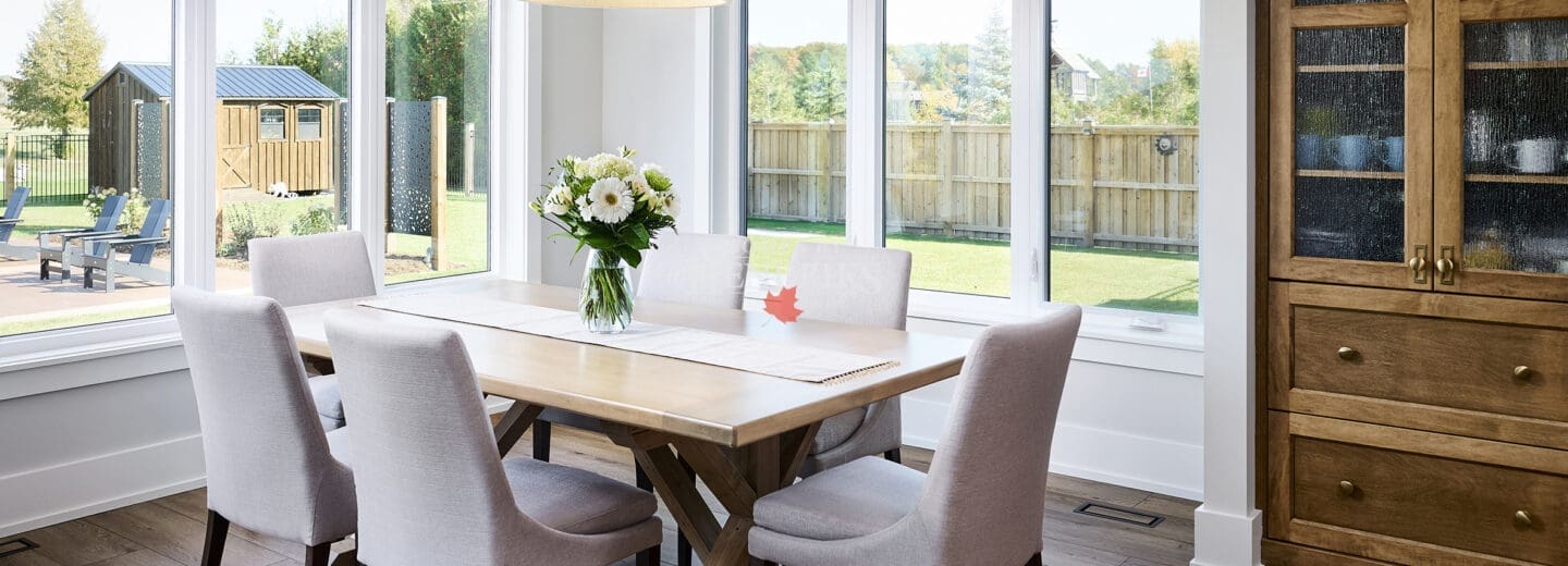 A spacious and elegant dining room featuring a large, custom wood dining table surrounded by comfortable seating.
