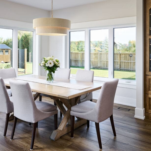 A spacious and elegant dining room featuring a large, custom wood dining table surrounded by comfortable seating.