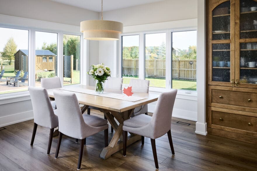 A spacious and elegant dining room featuring a large, custom wood dining table surrounded by comfortable seating.