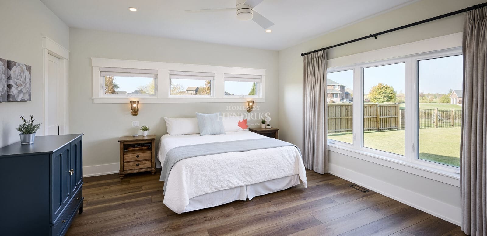 A spacious and tranquil primary bedroom featuring natural wood accents and soft, neutral tones