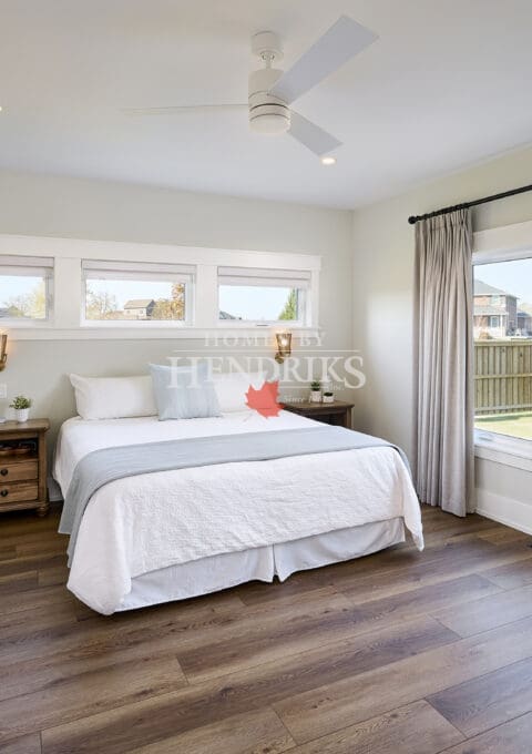 A spacious and tranquil primary bedroom featuring natural wood accents and soft, neutral tones