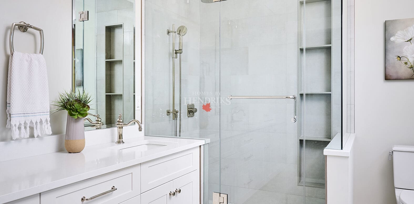 The primary ensuite design is enhanced by natural stone countertops and elegant lighting, creating a serene and sophisticated space.