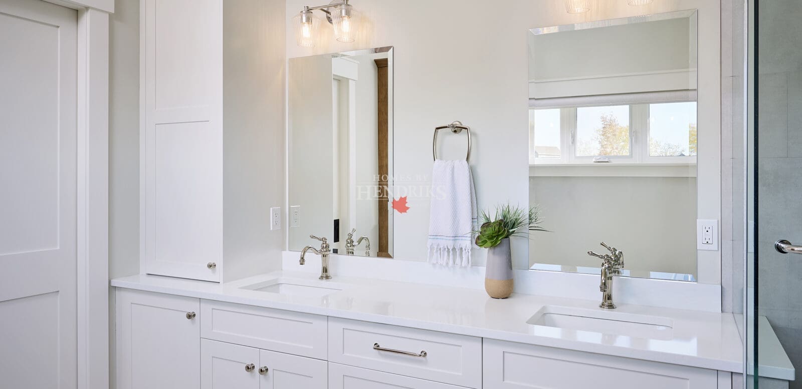 A stylish primary ensuite featuring crisp white cabinetry that offers a clean, modern look. The cabinets provide ample storage while maintaining a bright and airy atmosphere, complemented by sleek hardware and a neutral color palette.