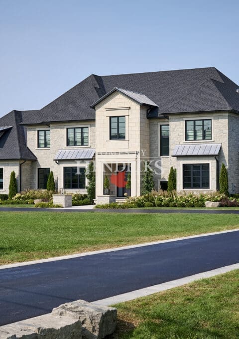 Charming custom home with a natural stone exterior, limestone accents, and a picturesque pool surrounded by manicured landscaping.