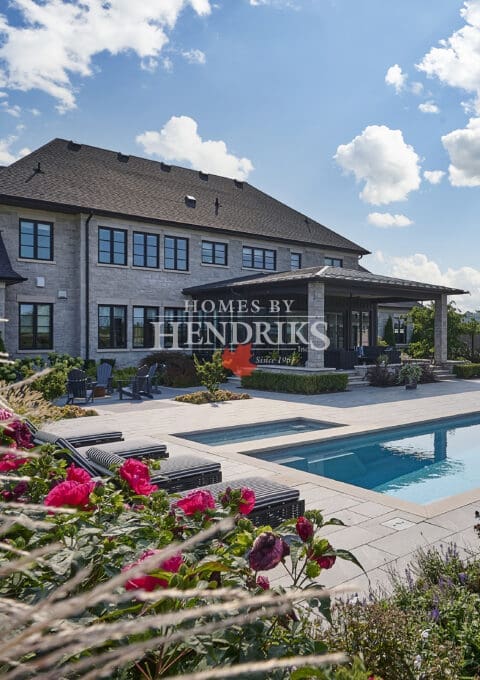 View of a modern home with an inground pool surrounded by lush landscaping.