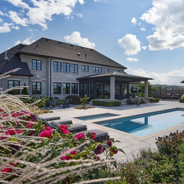 View of a modern home with an inground pool surrounded by lush landscaping.