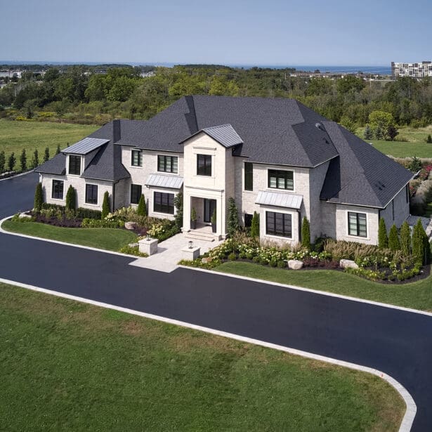 Stunning custom-built home with a luxurious stone façade, limestone accents, and a gorgeous pool set in a beautifully landscaped yard.