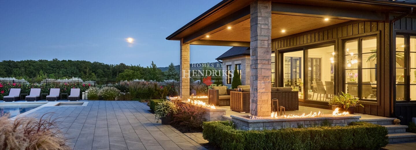 Impressive custom home with a stone exterior, limestone accents, and a beautifully landscaped yard with a sparkling pool.