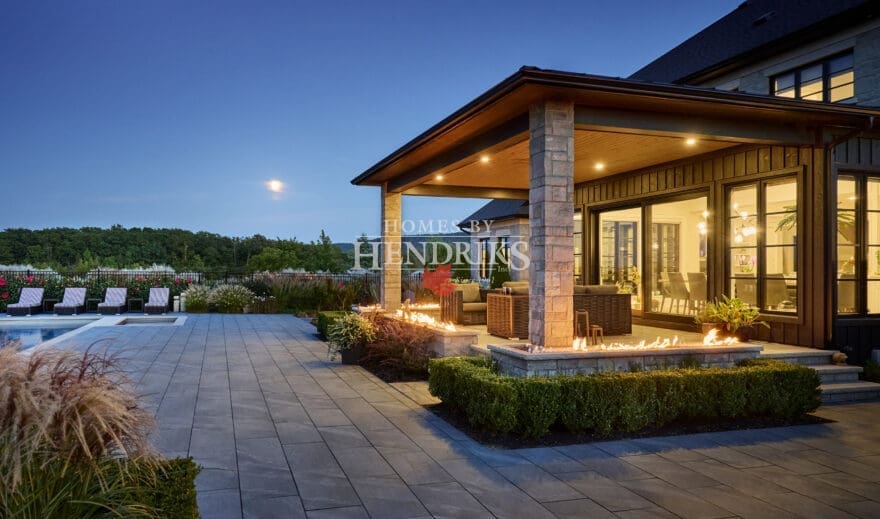 Impressive custom home with a stone exterior, limestone accents, and a beautifully landscaped yard with a sparkling pool.