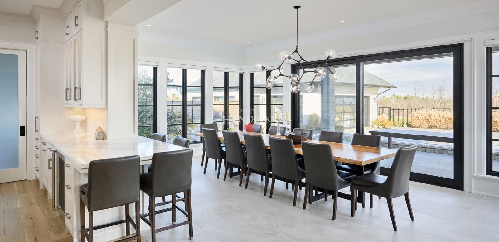 Open dining area with a large table, modern light fixture, and expansive windows.