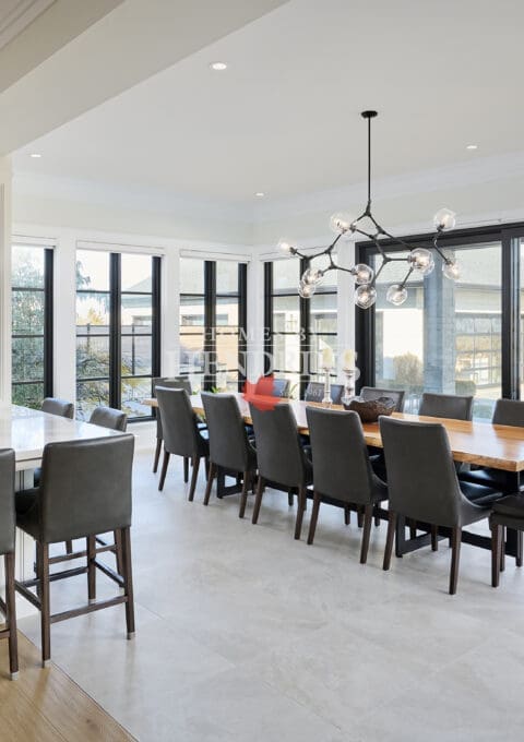 Open dining area with a large table, modern light fixture, and expansive windows.