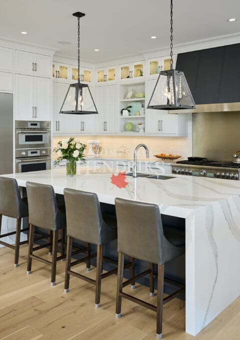 Oversized kitchen island with waterfall countertops and seating for guests.