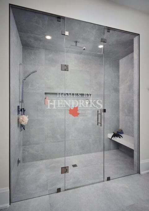 Walk-in tiled shower with glass enclosure, modern fixtures, and built-in niches.