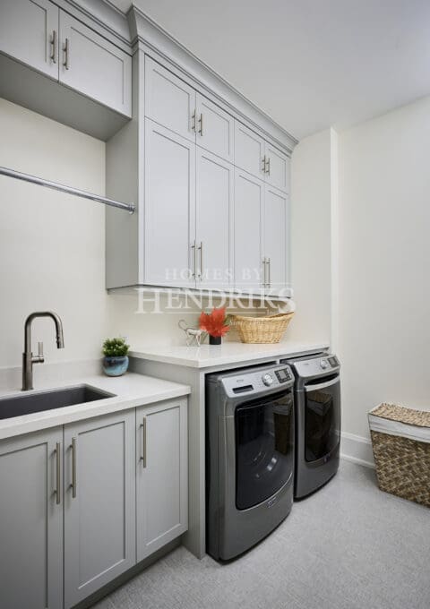 Laundry room with front-load machines, a folding counter, and organized cabinetry.