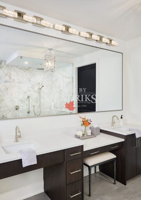 Luxury bathroom with dual vanities, white quartz countertops, and dark wood cabinetry. Large illuminated mirror and marble shower enclosure with glass walls