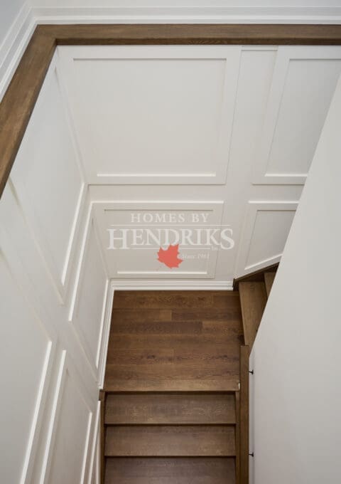 View down a custom stairwell featuring white paneled walls and rich oak treads for a clean, transitional design.