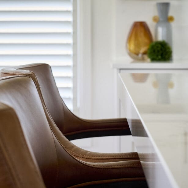 Leather seating and decorative accents at a quartz kitchen island, combining function and refined design.