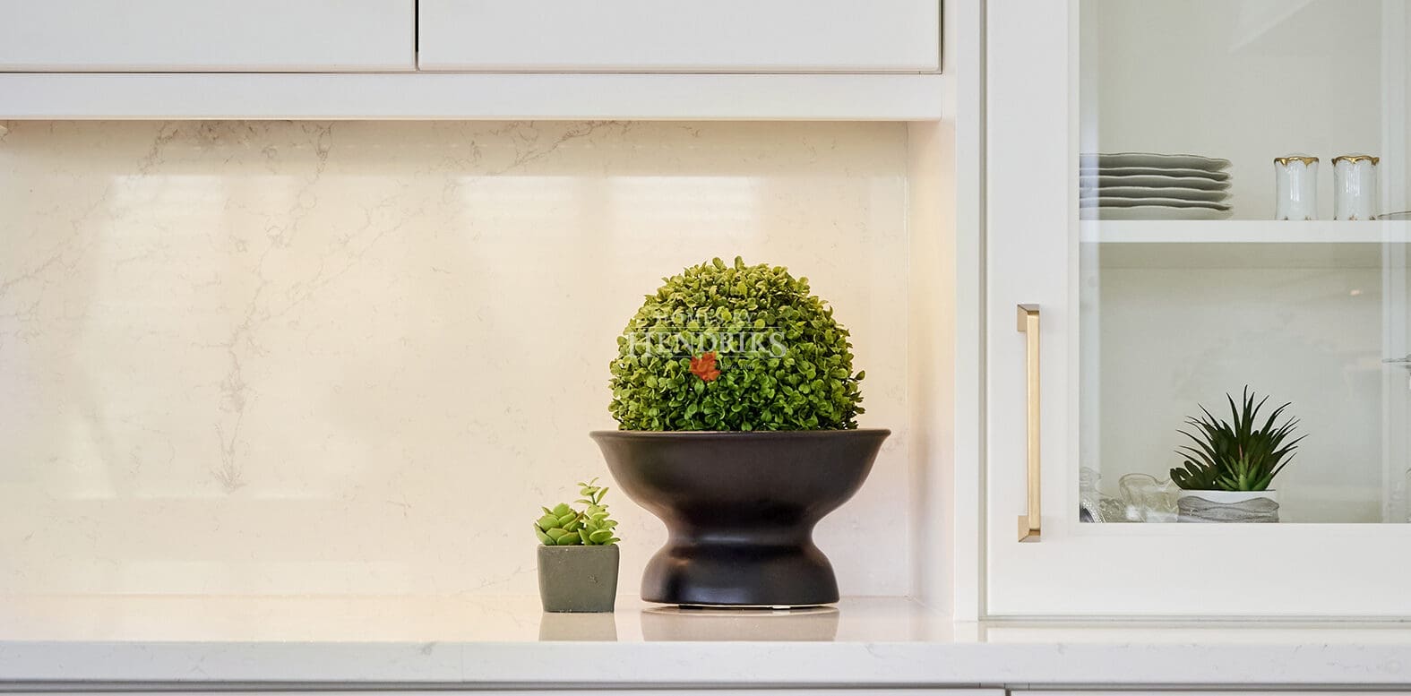Custom cabinetry with open shelving for fine dishware and styled greenery, featuring soft integrated lighting.