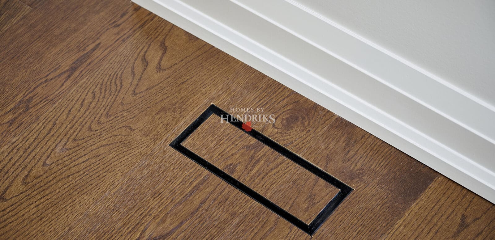 Discreet floor vent integrated seamlessly into oak hardwood flooring with matching trim for a clean architectural finish.