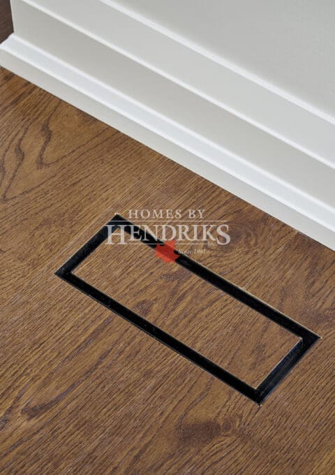 Discreet floor vent integrated seamlessly into oak hardwood flooring with matching trim for a clean architectural finish.