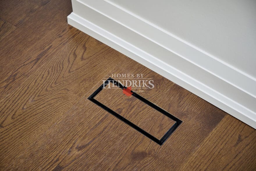 Discreet floor vent integrated seamlessly into oak hardwood flooring with matching trim for a clean architectural finish.