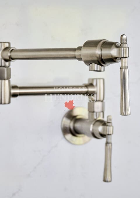 Brushed nickel wall-mounted pot filler against a soft marble backsplash, combining practicality with refined kitchen design.