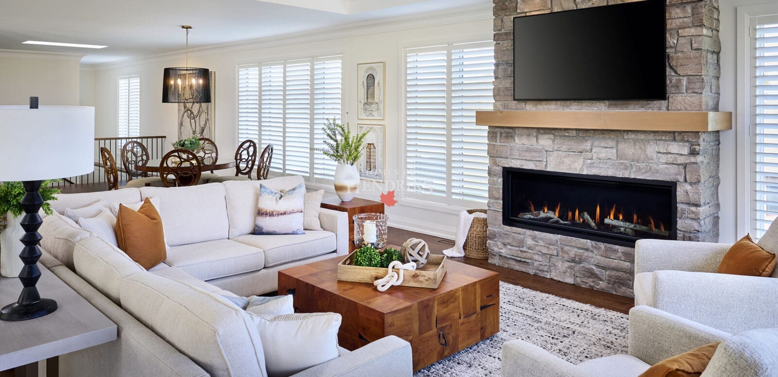 Open-concept living and dining area blending rustic stone, modern lighting, and layered neutral furnishings in a bright, inviting space.