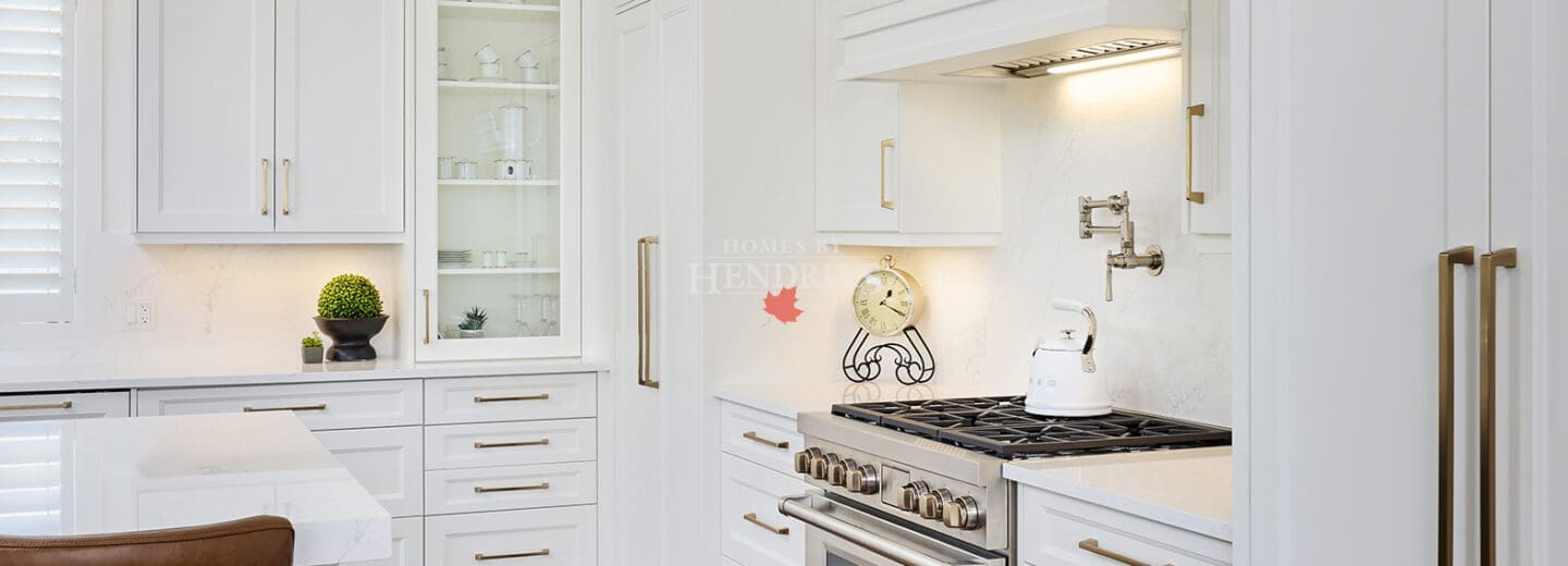 Contemporary kitchen with Wolf range, built-in hood, white quartz backsplash, and elegant crown moulding.