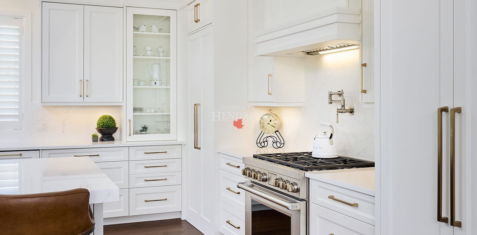 Contemporary kitchen with Wolf range, built-in hood, white quartz backsplash, and elegant crown moulding.