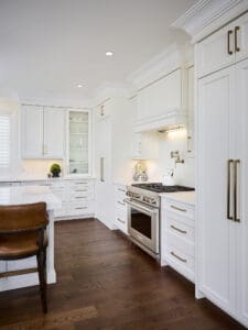 Contemporary kitchen with Wolf range, built-in hood, white quartz backsplash, and elegant crown moulding.