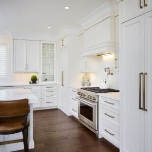 Contemporary kitchen with Wolf range, built-in hood, white quartz backsplash, and elegant crown moulding.