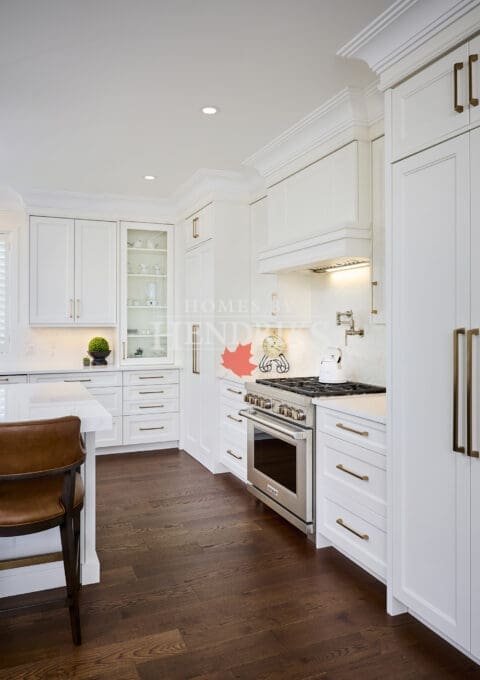Contemporary kitchen with Wolf range, built-in hood, white quartz backsplash, and elegant crown moulding.